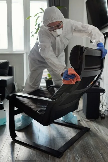 Two women in red overalls vacuuming and sweeping a modern living room.